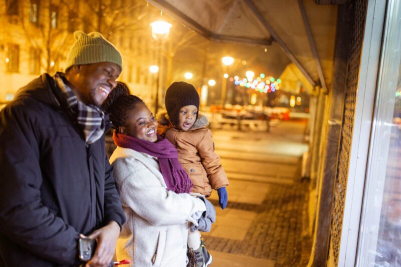 A cheerful family of three enjoys a winter evening window shopping in the city. 