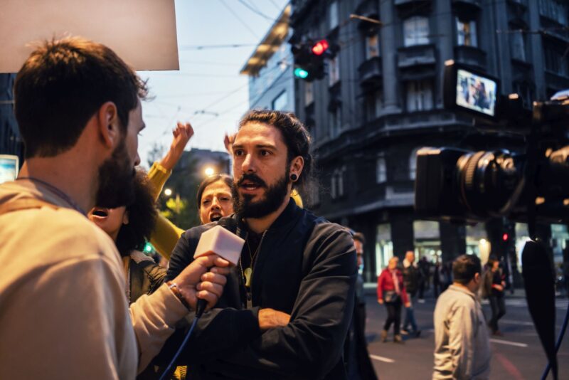Man being interviewed by a reporter in the street