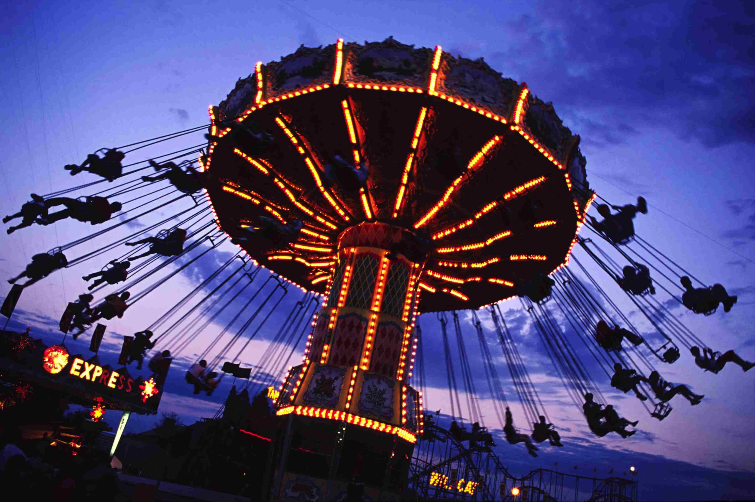 Amusement park giant swing ride, lit up against a purple sky