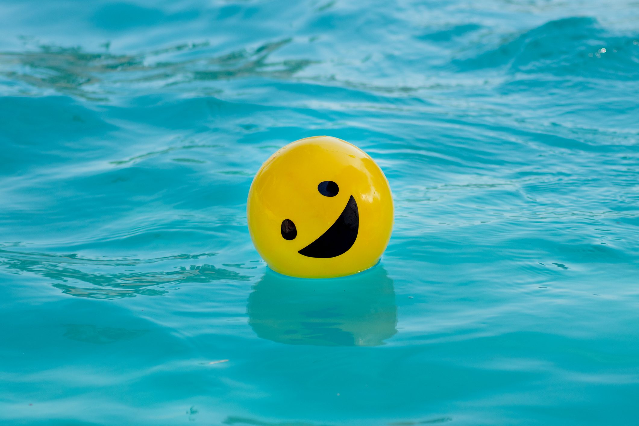 Yellow ball with a smiling face floating on the swimming pool