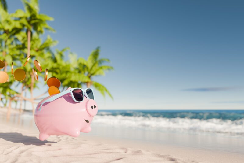 A piggy bank runs along the beach toward the water, shedding coins