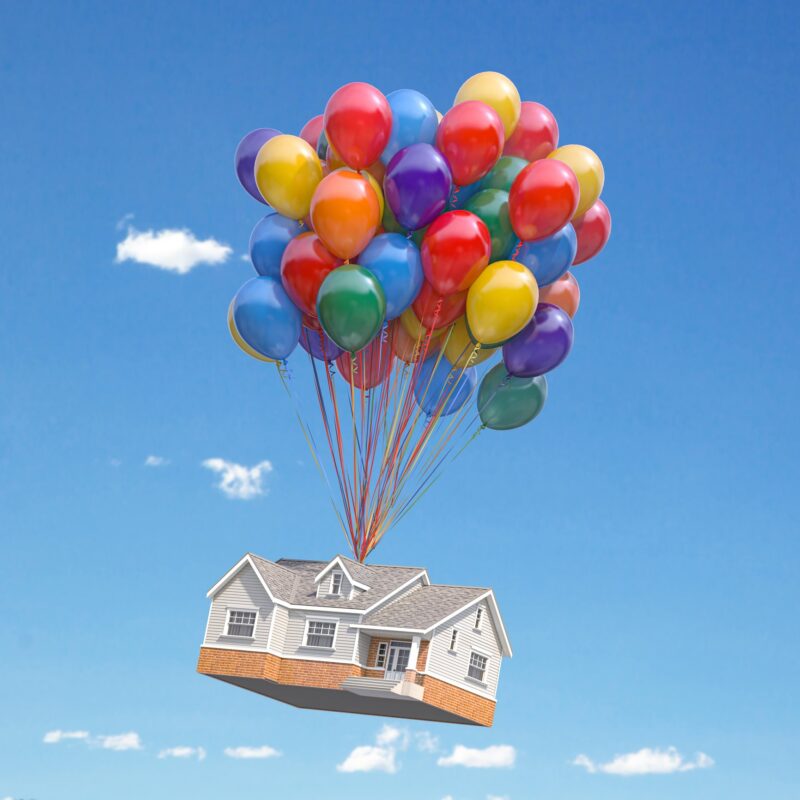 House with balloons bunch flying in the sky.