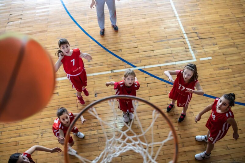 Female  School Basketball Team waiting to see if ball goes in the basketball hoop