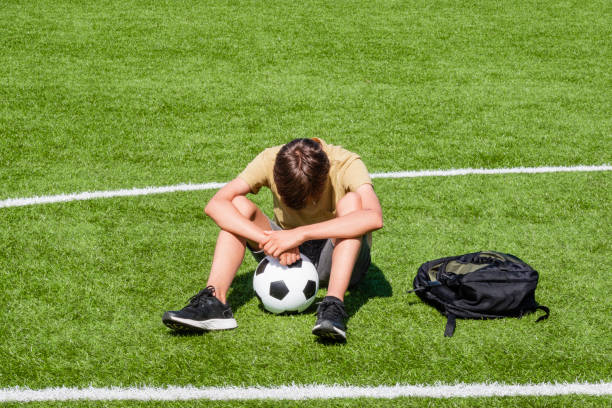Teenage boy sitting on soccer field