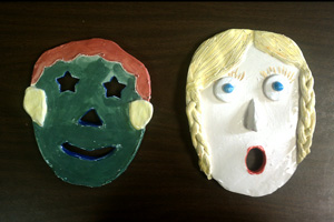 Two clay masks of human faces created as a fourth grade art project